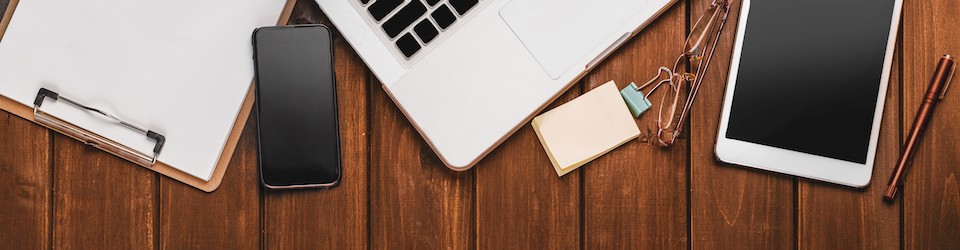 Top View of Modern Technology working Place on wooden Office Desk with large Desktop Computer Coffee Mug Keyboard and Mouse green Flower Notepad and Pen