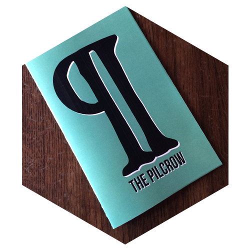 Hexagon shaped image of a teal colored book called "The Pilcrow" on a wooden talble, links to Opportunities for companies and agencies