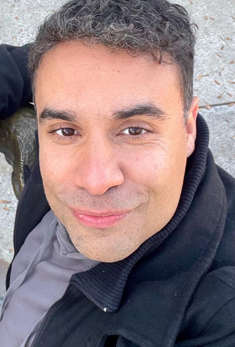 Julio Torres is looking up at the camera with a smile.